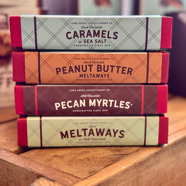 Stack of chocolate bar boxes with different flavors on a wooden surface